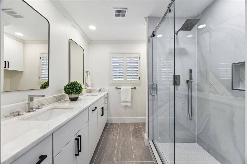 Stylish primary ensuite with double sinks, frameless waterfall shower and commode.