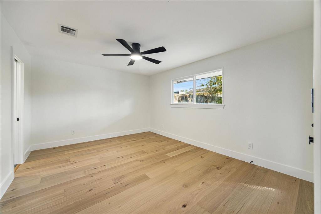 Spare bedroom with gleaming hardwood floors and neutral color palette. Modern contemporary ceiling fansinstalled throughout.