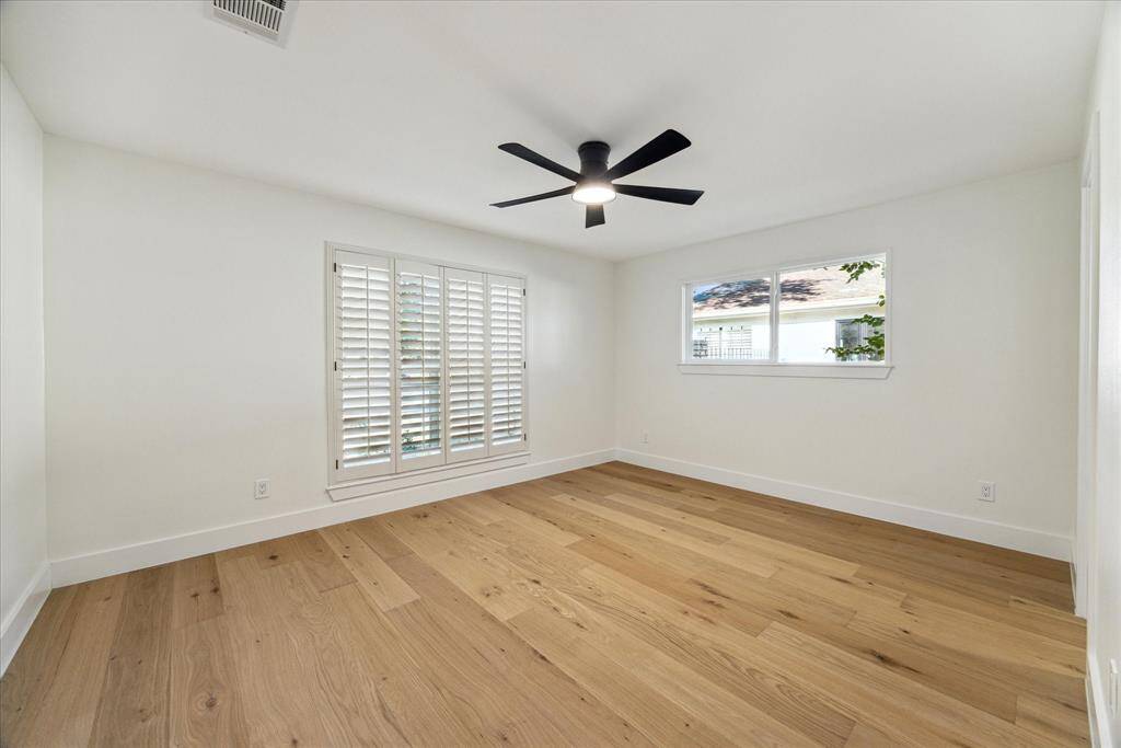 Spare bedroom with gleaming hardwood floors and neutral color palette. Modern contemporary ceiling fans installed throughout.