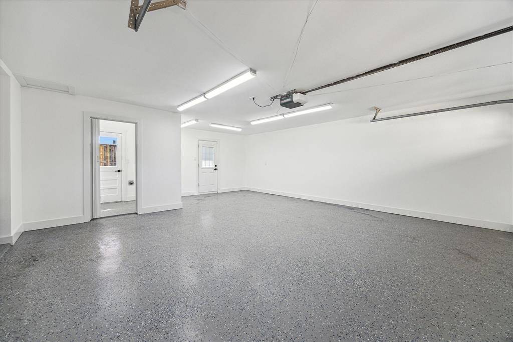 Oversized double garage with epoxy flooring and adjacent half bath with backyard pool access