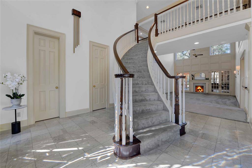This is a spacious, bright entryway featuring an elegant curved staircase, tiled floors.