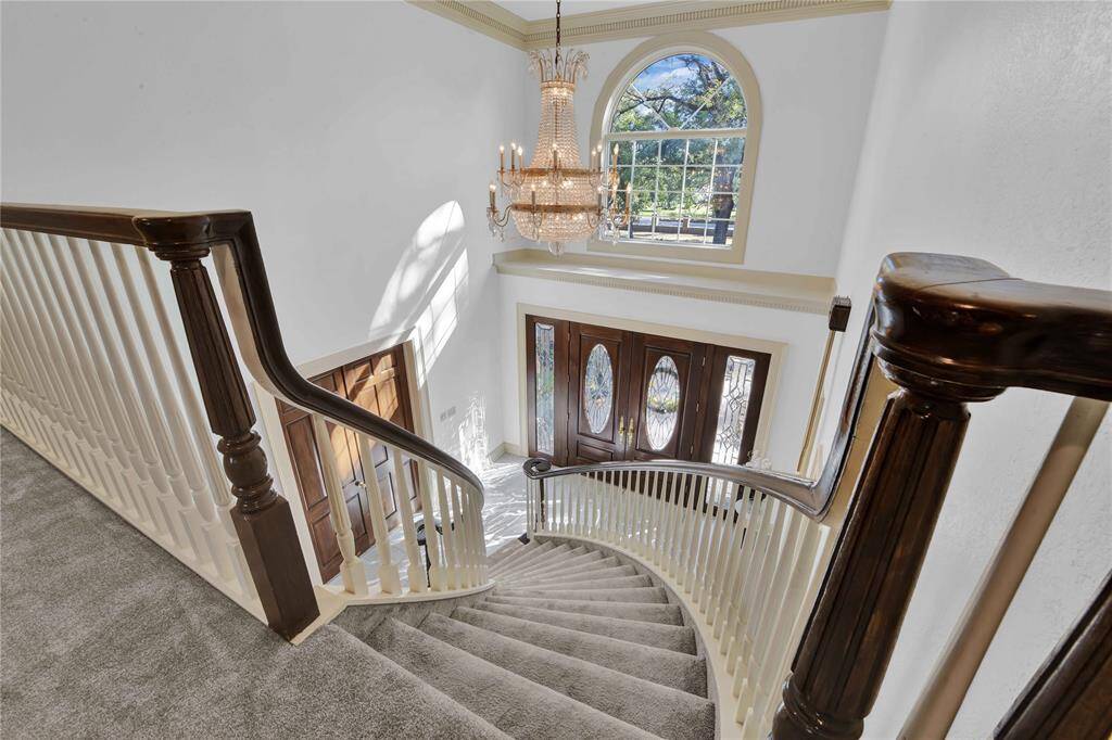 Grand staircase leads to foyer with a decorative front door and a large arched window that allows for plenty of natural light. A chandelier adds a touch of luxury to the high-ceilinged area. Chandelier is negotiable.