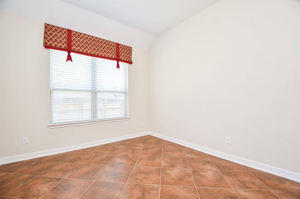 Bright and versatile room with a large window, tiled floors, and neutral walls.