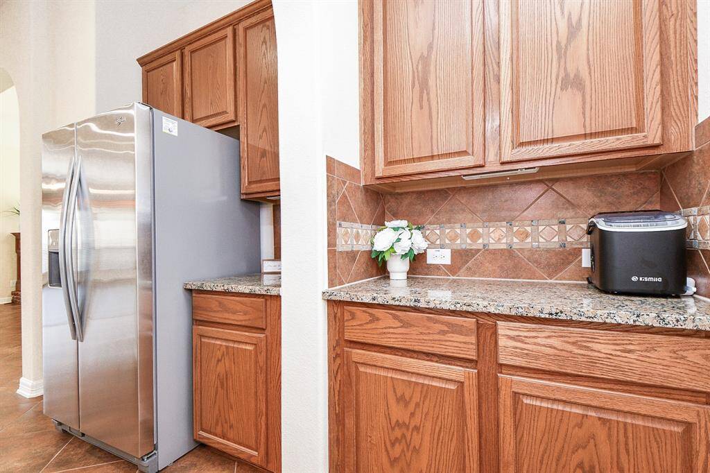 This kitchen features stainless steel appliances, granite countertops, and warm wood cabinets. The backsplash adds a decorative touch, and there's ample storage space.