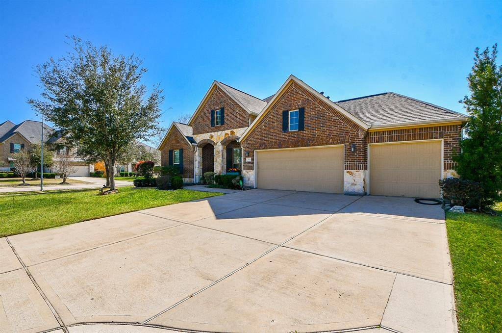 This home features a charming brick exterior with a spacious three-car garage. The well-maintained front lawn and trees add curb appeal, and the driveway offers ample parking space.
