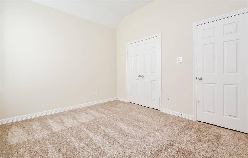 This photo shows a bright, neutral-colored room with clean, plush carpeting. It features two white doors, one likely a closet, and a simple, modern design. Ideal for a bedroom or home office.
