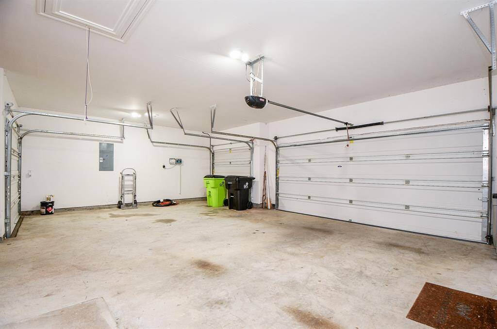Spacious two-car garage with clean, white walls and ample lighting. It features two large garage doors, a few utility items, and some storage space, perfect for vehicles and additional storage needs.
