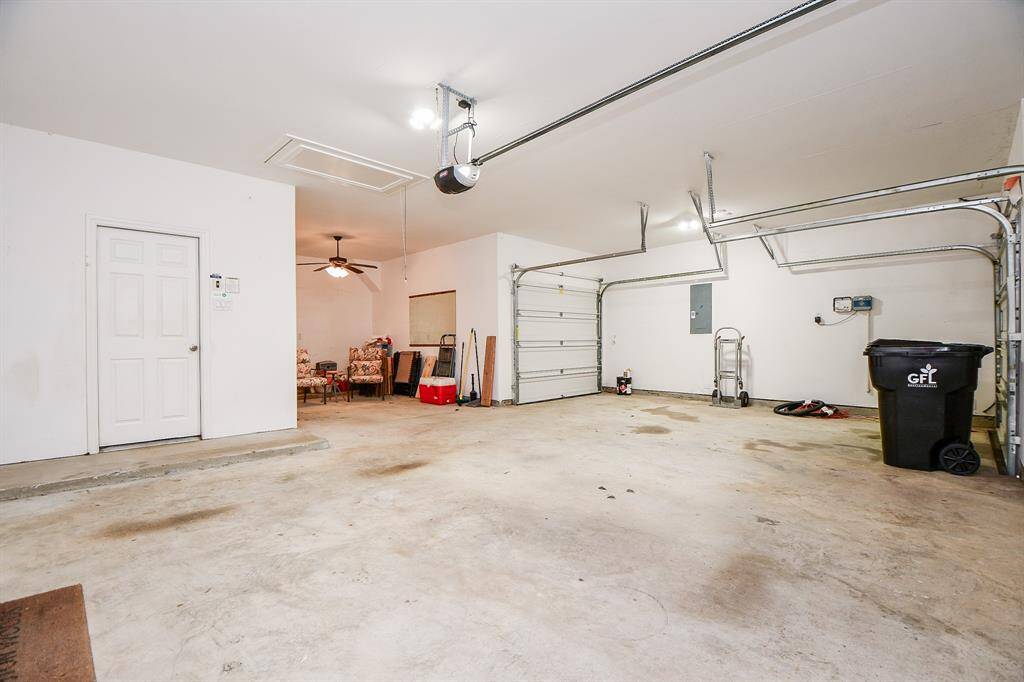 This spacious garage features a clean, open layout with room for two vehicles. It includes a side door for easy access, overhead lighting, and additional space for storage or a small workshop area.