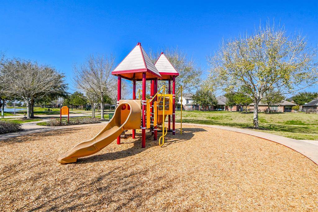 This photo features a community splash pad with vibrant blue water features, surrounded by a fence and trees, providing a fun and refreshing outdoor space for families.