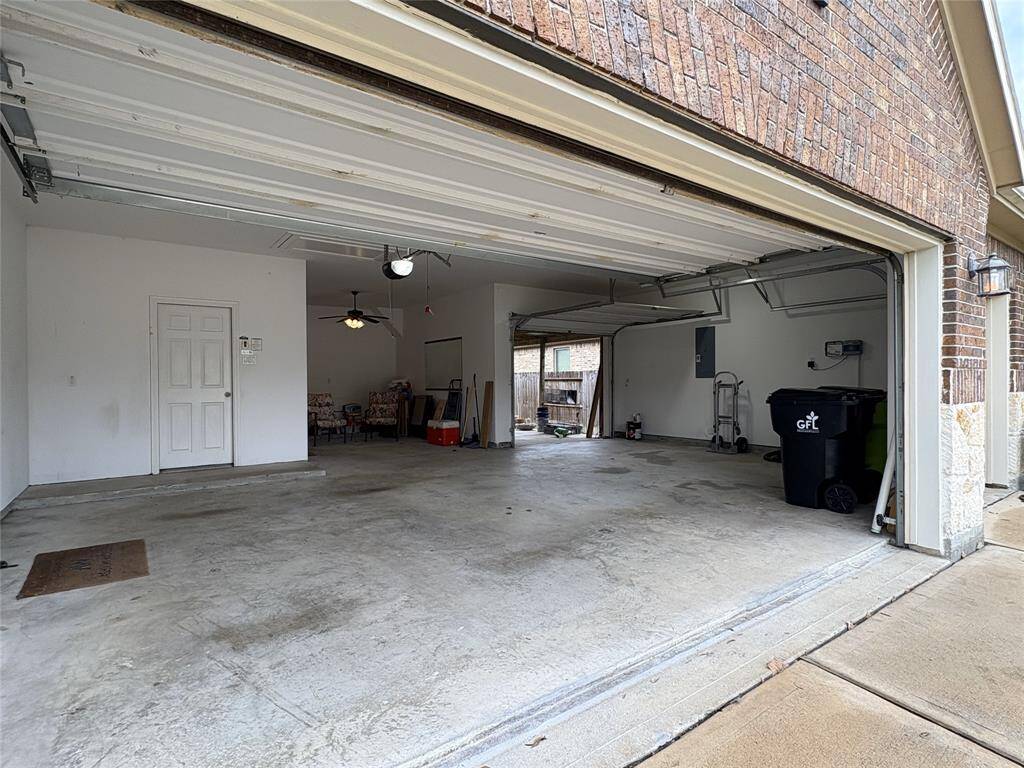 Charming brick home with a well-maintained lawn, featuring a welcoming stone archway entrance. The property includes a spacious three-car garage, decorative shrubs, and mature trees, offering great curb appeal.