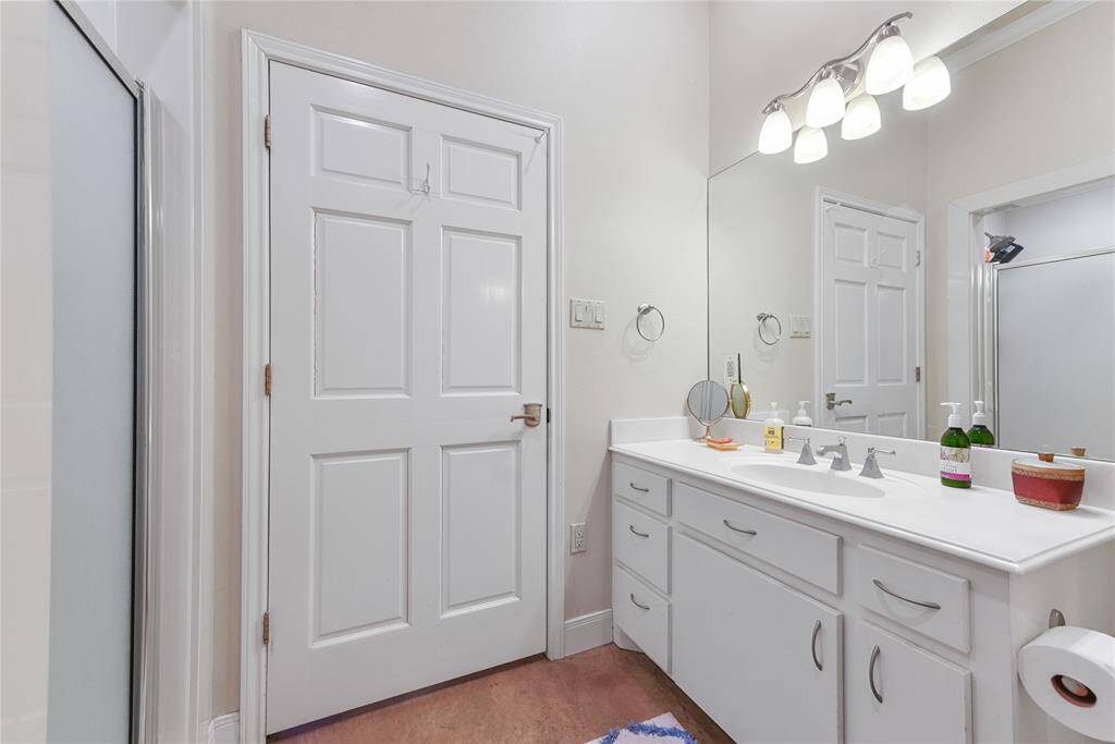 The pool house guest suite full bath features vanity storage with single sink; shower; commode; and stack washer and dryer.