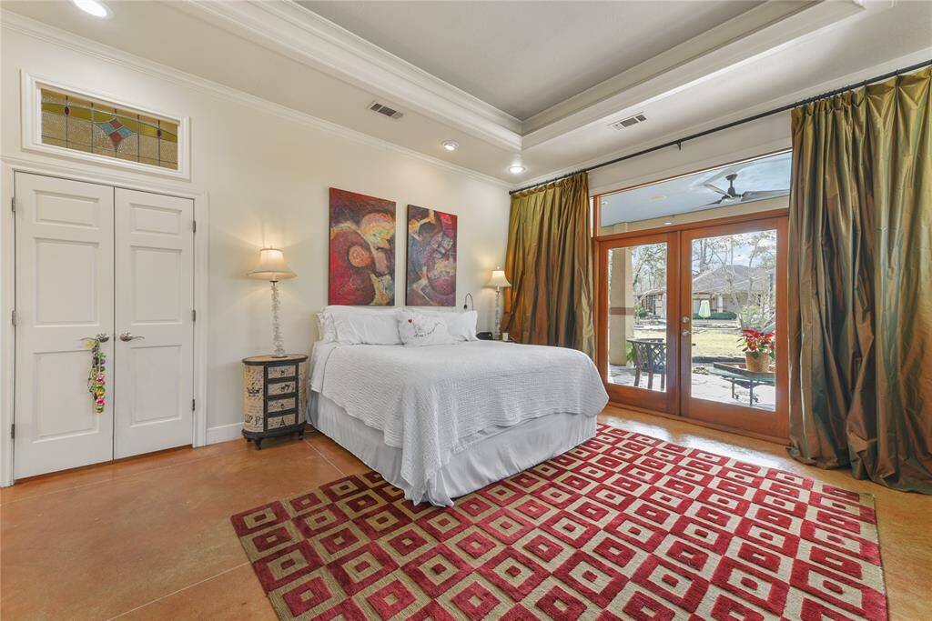 Another view of the lovely, spacious Primary Suite in the rear home on the property.  Note the stained glass transom above the double door entry.  Underneath, stained concrete flooring for ultimate easy care!