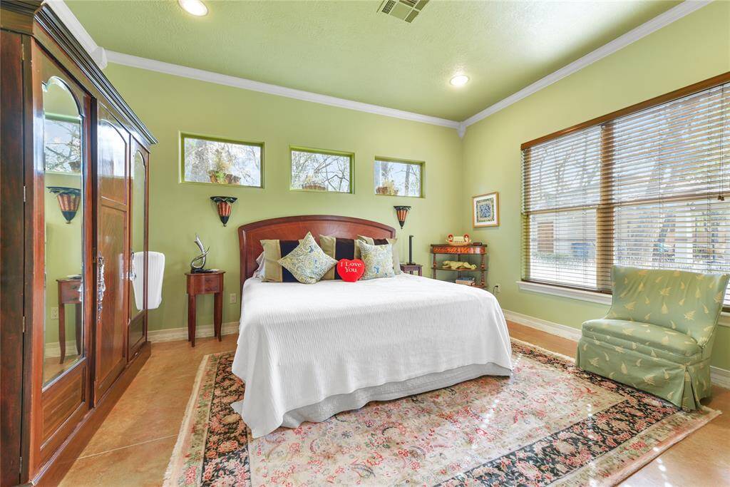 The bright and cheerful second bedroom again has the high ceilings and plenty of windows for showers of natural light.  Stained concrete flooring, recessed lighting, and crown moldings highlight this room, which also has an en-suite bath.