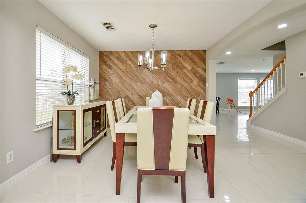 Natural light streams in from large windows, creating a warm and inviting ambiance, complemented by the neutral-toned walls and light-colored tiled floor.