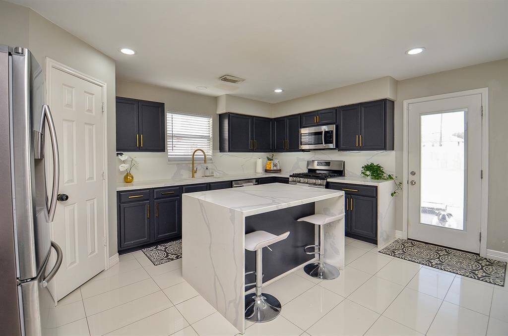 The large island, with its pristine white countertop, provides ample workspace