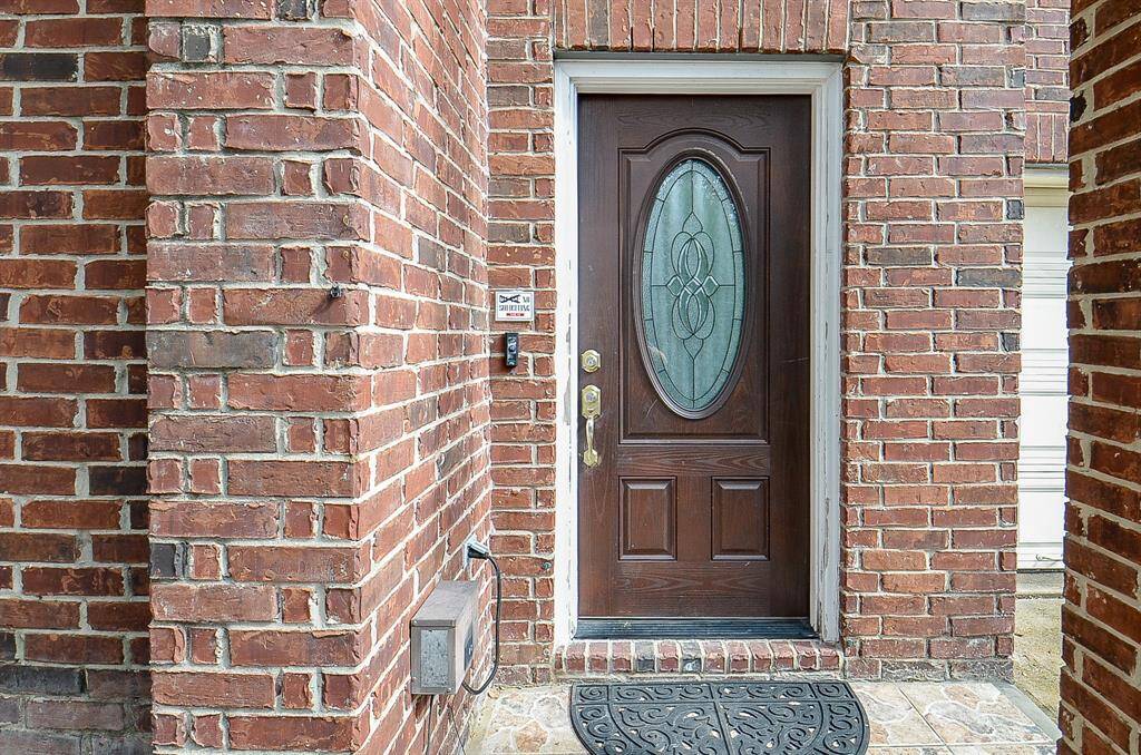 With its spacious two-story layout, the home features a grand entrance framed by an archway, leading to a beautifully designed wooden front door with an oval-shaped frosted glass panel.