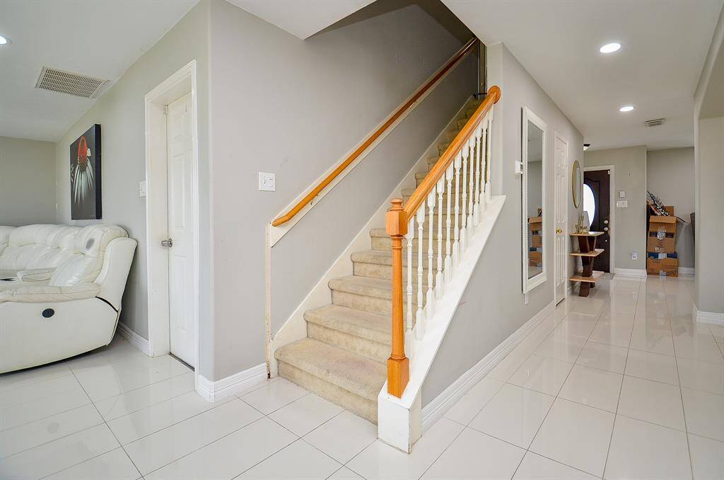The light-colored wooden staircase, paired with pristine white balusters, creates a striking focal point that seamlessly connects the lower and upper levels of the home.