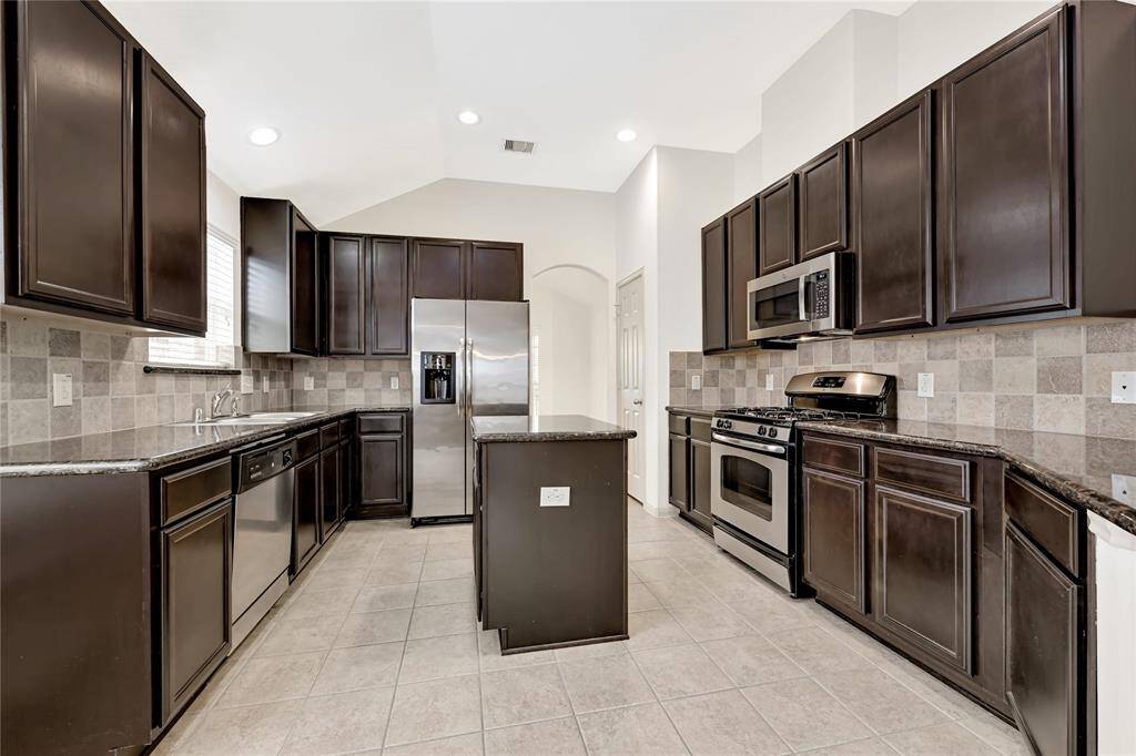 The deep and warm tones of the cabinets match well with the neutral tile floor, white painted ceiling and neutral wall color scheme. The Stainless Steel refrigerator also conveys with the sale of this home!
