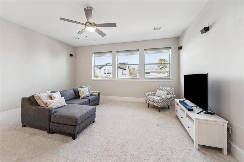 Spacious game room featuring large windows, soft carpeting, and recessed lighting for a bright yet cozy atmosphere. Wall-mounted speakers provide an opportunity for a home theater setup, while the open layout offers plenty of flexibility for entertainment or relaxation. Positioned on the second floor, this versatile space is ideal for gatherings, movie nights, or a playroom.