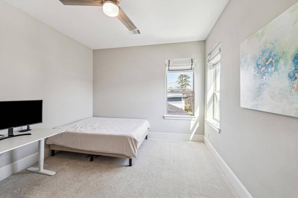 This secondary bedroom offers a peaceful retreat with neutral tones, abundant natural light, and soft carpeting for a cozy feel. The ceiling fan enhances comfort, while multiple windows provide a bright and inviting atmosphere. Ideal as a guest suite, home office, or additional bedroom, this space adapts to various needs with ease.