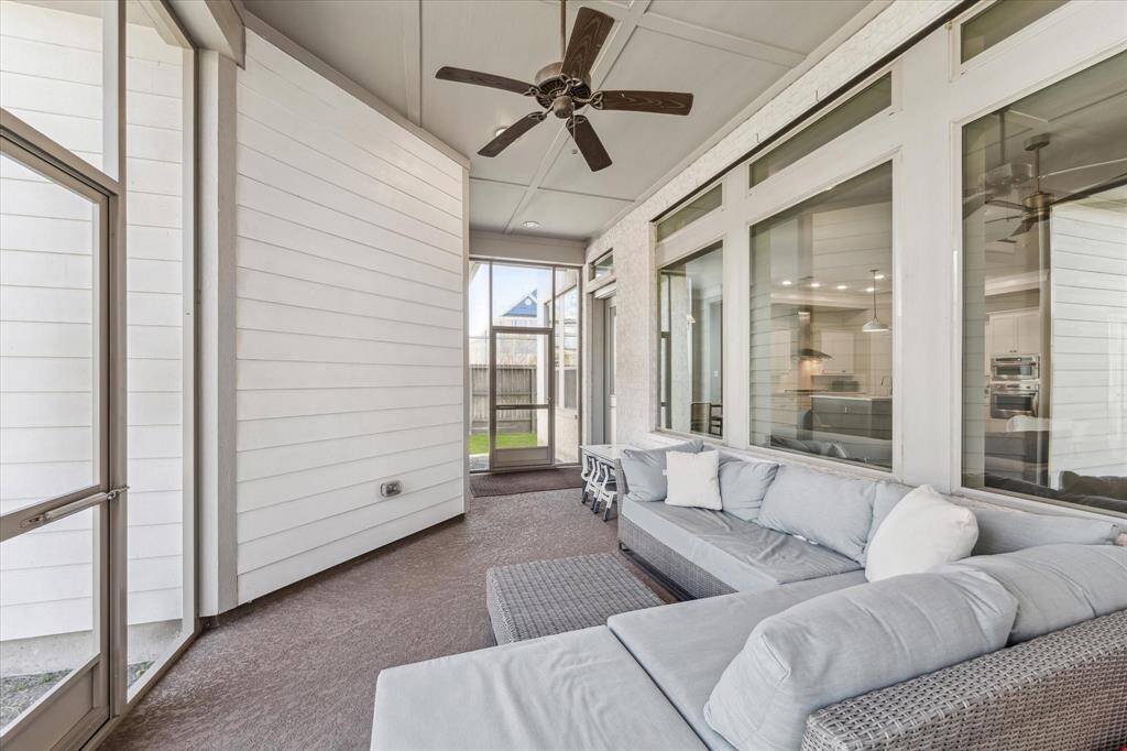 A spacious screened-in patio designed for year-round enjoyment. Large windows provide a connection to the interior living space, while the ceiling fan ensures a comfortable breeze. The covered design allows for outdoor relaxation, protected from the elements, making it an ideal spot to unwind or entertain.