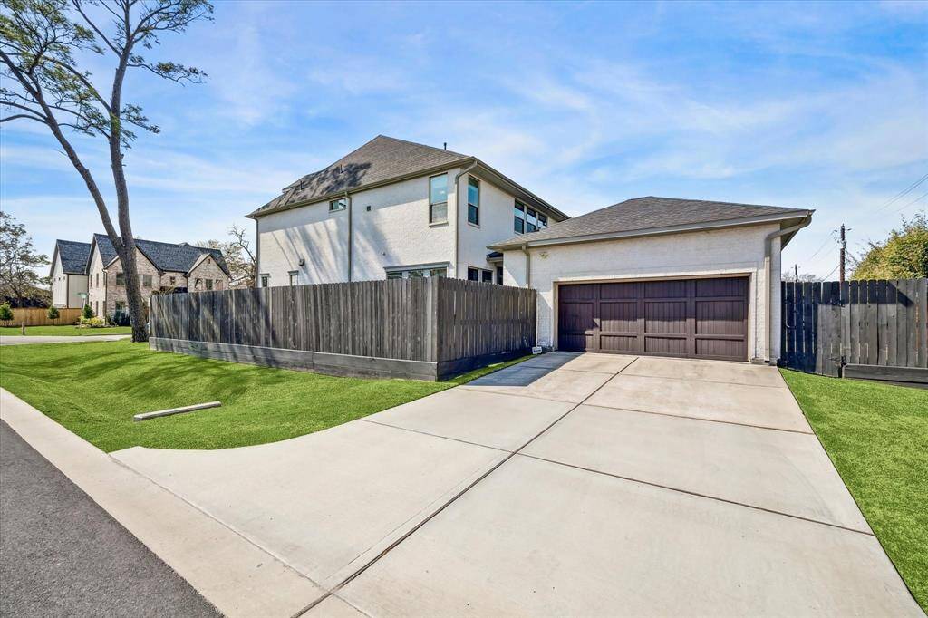 Detached two-car garage with a dark wood door complements the home's aesthetic while providing secure parking and additional storage. A fenced backyard ensures privacy, while the extended driveway offers extra space for guest parking. Positioned on a corner lot, the home benefits from additional yard space and enhanced curb appeal.