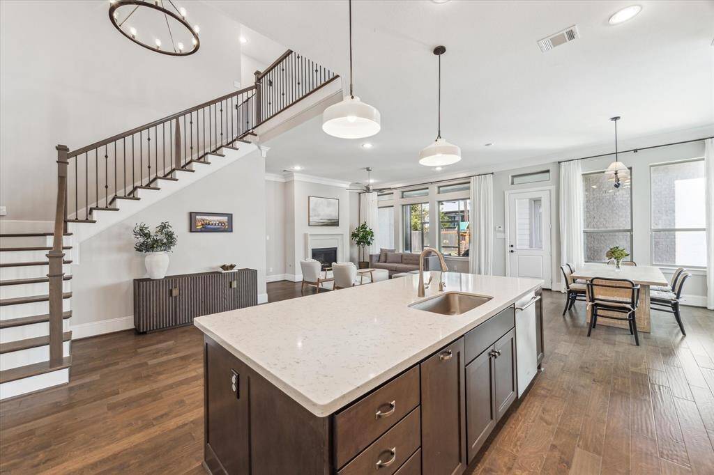 This expansive kitchen overlooks the dining area and living room, creating a seamless space for entertaining and everyday living. A statement staircase with iron railings leads to the second floor, complementing the high ceilings and abundant natural light. The adjacent dining area and backyard access make this layout as functional as it is stylish.