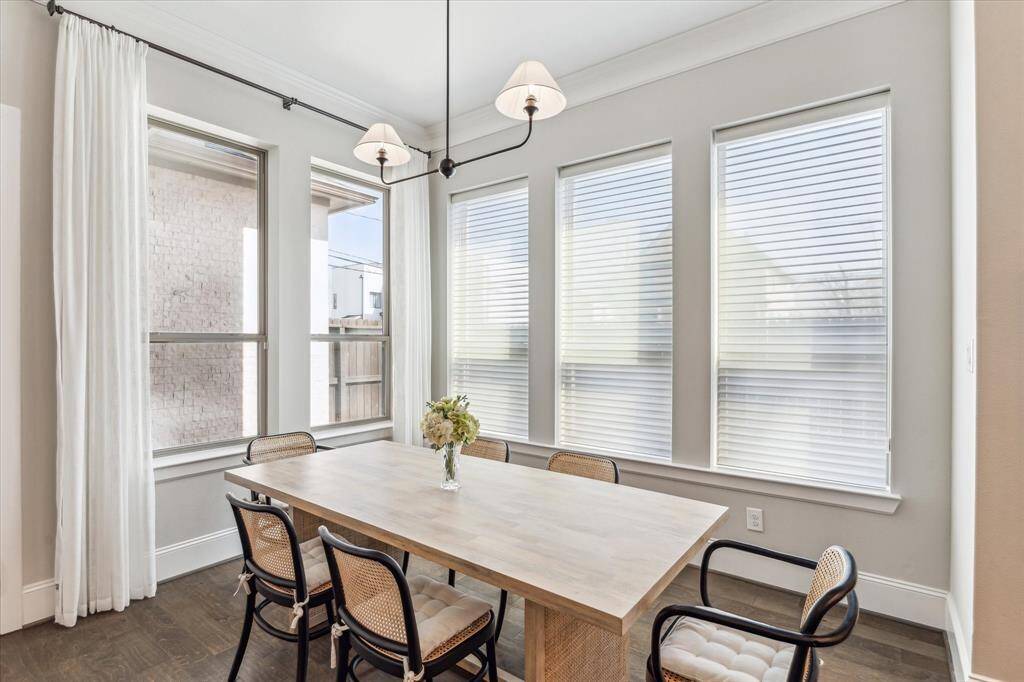 A bright and airy dining room featuring floor-to-ceiling windows that bring in abundant natural light. Elegant crown molding and a statement light fixture add timeless charm, making this space perfect for both everyday meals and special gatherings.