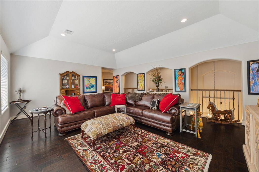 ARCHED OPENINGS ACCENTED WITH DECORATIVE IRON RAILINGS OVERLOOK THE STAIRCASE
