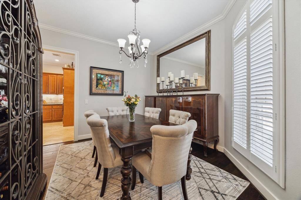 FORMAL DINING ROOM - neutral decor with wood flooring, elegant chandelier, plantation shutters