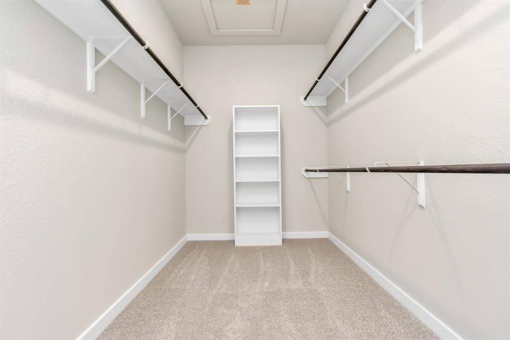 Primary bedroom walk-in closet that epitomizes luxury and practicality. This generously sized space features built-in shelving, offering abundant room for impeccable organization. High ceilings and recessed lighting create a bright and welcoming ambiance. Sample photo of completed home with similar floor plan. Actual colors and selections may vary.