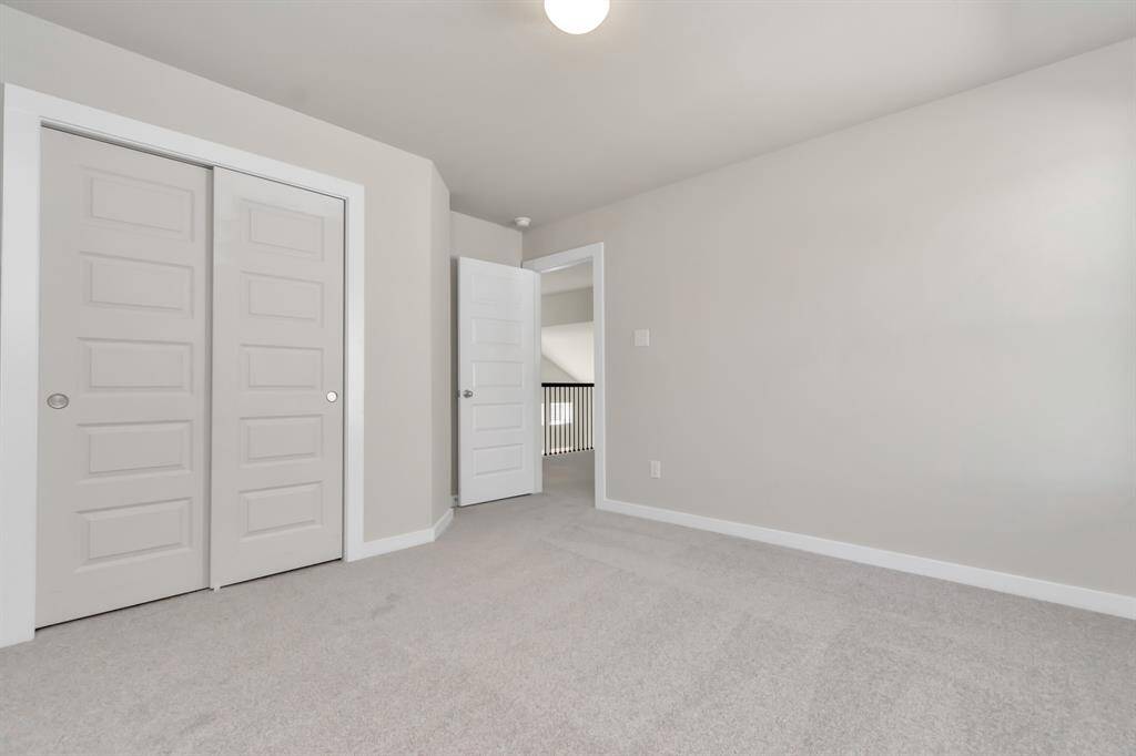 Secondary bedrooms showcase 5-panel doors adorned with modern hardware, large windows enhanced by privacy blinds, and spacious closets featuring sleek and contemporary finishes. Sample photo of completed home with similar floor plan. Actual colors and selections may vary.