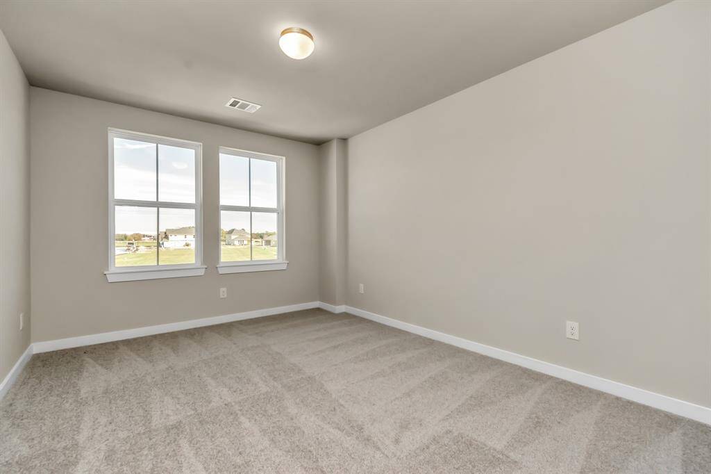 Secondary bedrooms showcase 5-panel doors adorned with modern hardware, large windows, and spacious closets featuring sleek and contemporary finishes. Sample photo of completed home with similar floor plan. Actual colors and selections may vary.