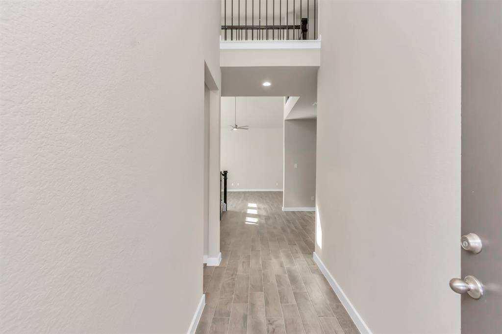 The majestic entryway allures with its high ceilings, embellished with sophisticated wood-look tile flooring and sleek oversized baseboards. Lift your eyes to a captivating sight of the open staircase, and follow the trail of natural light pouring in through expansive windows as you journey to the family room, crafting an inviting and cozy ambiance.