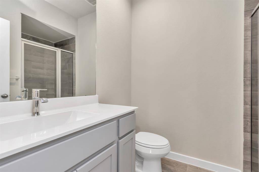 Experience sophistication in the guest suite bathroom, where tile flooring complements a walk-in shower with tile surround. Light wood cabinets complete with a beautiful light countertop, enhances the space for a truly inviting ambiance.