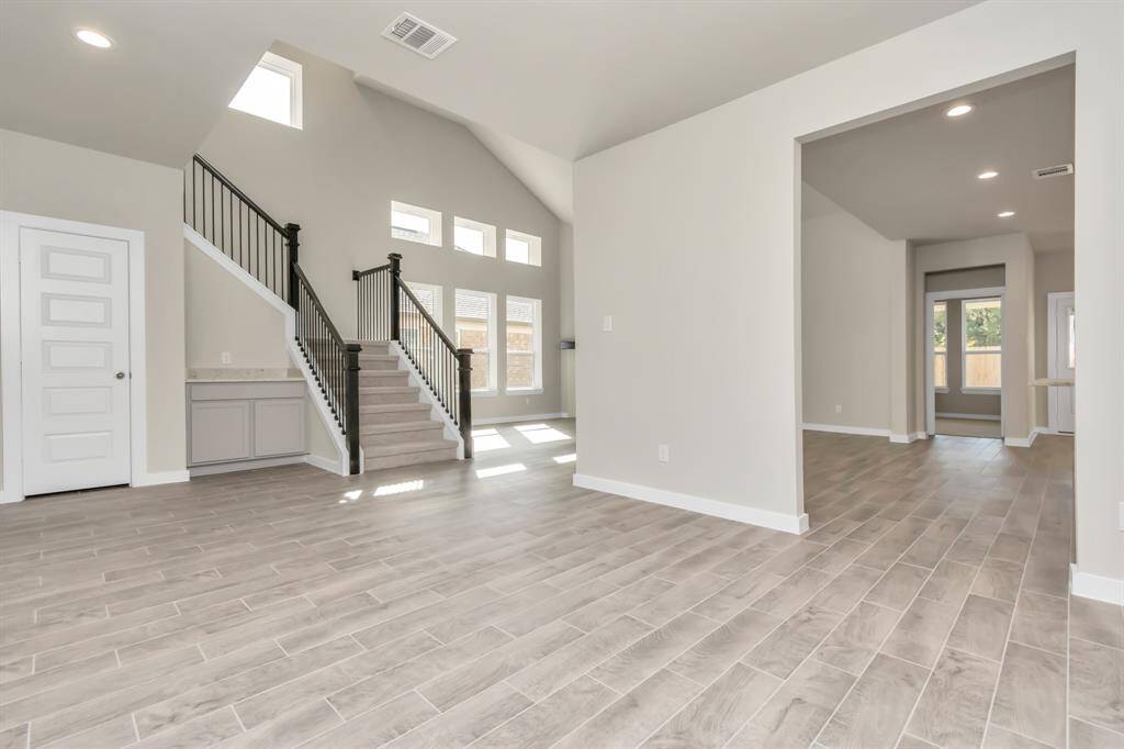 View from the enticing dining area intricately integrated into the open concept, linking the family room and kitchen. Immerse yourself in the allure of the striking floors, recessed lighting, and calming paint palette.