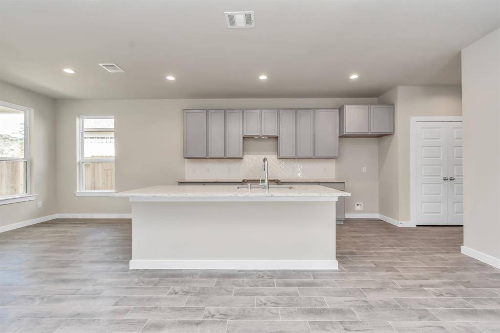Experience the epitome of a dream kitchen in this generously spacious layout! Revel in features like a massive granite island, high ceilings, soft-close cabinets, granite countertops, stainless steel appliances, a sleek tile backsplash, and recessed lighting. With an open concept design, this kitchen seamlessly connects to the expansive family room, creating a perfect and inviting hub for gatherings.