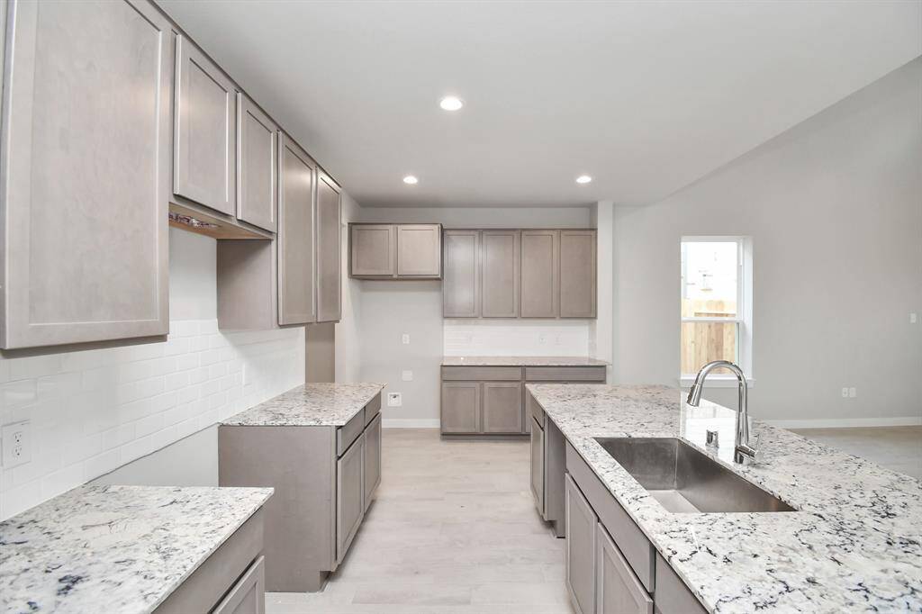 Discover another perspective of this stunning kitchen, sleek back splash, single basin sink, and generously appointed with an abundance of counter space. Sample photo of completed home with similar floor plan. Actual colors and selections may vary.