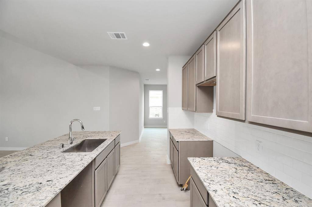The kitchen is a culinary haven, featuring granite countertops, a tile backsplash, stainless steel appliances, and 42” upper cabinets. Sample photo of completed home with similar floor plan. Actual colors and selections may vary.