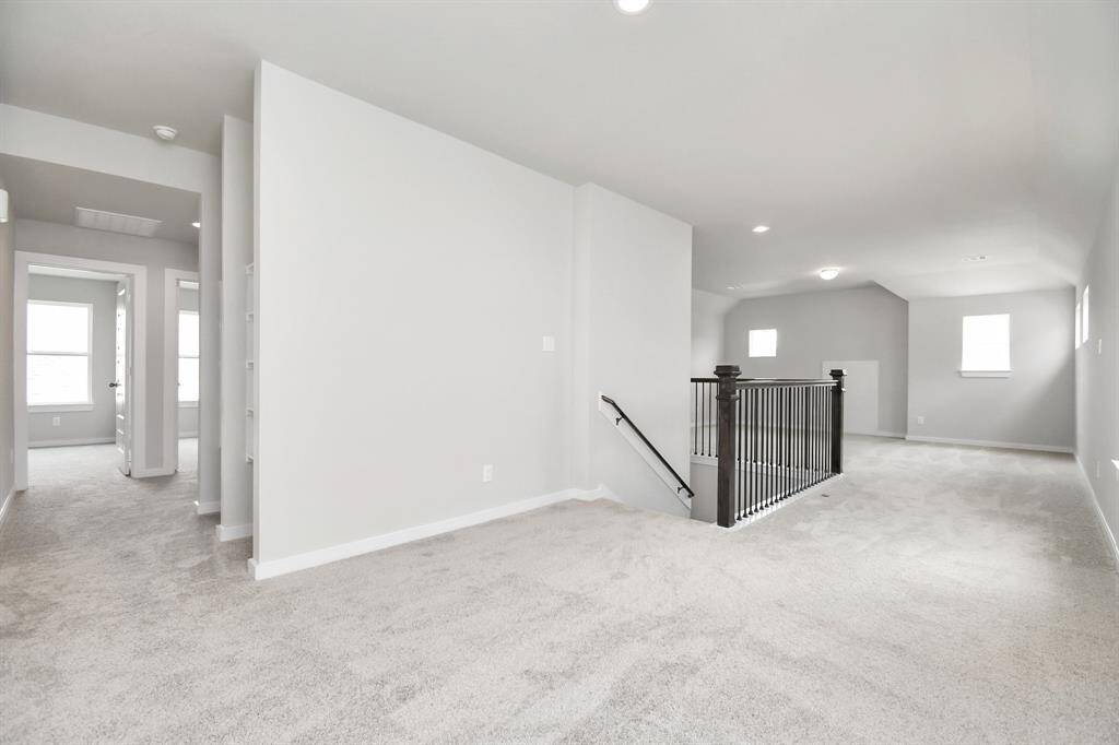 Ascend to the openness: The modern and dark rail stains, coupled with sleek metal balusters, infuse this loft area with a spacious and contemporary ambiance. Sample photo of completed home with similar floor plan. Actual colors and selections may vary.