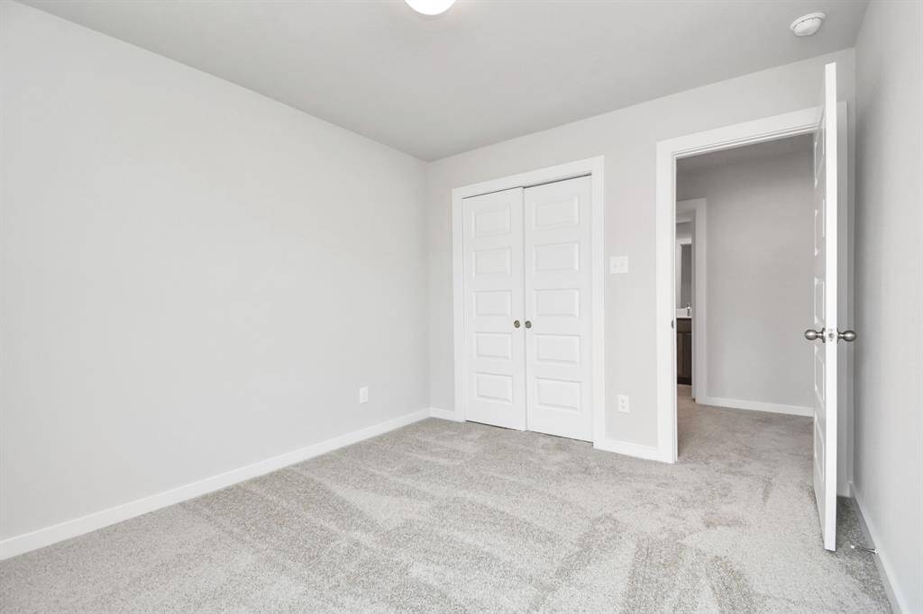 Secondary bedrooms showcase 5-panel doors adorned with modern hardware, large windows enhanced by privacy blinds, and spacious closets featuring sleek and contemporary finishes. Sample photo of completed home with similar floor plan. Actual colors and selections may vary.