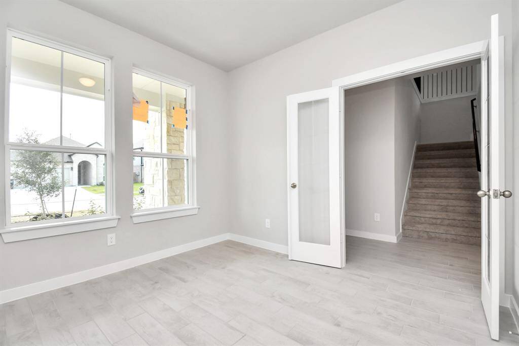 Quietly nestled in front of the home is the sophisticated home office. Featuring plush premium flooring custom paint, and large windows. Sample photo of completed home with similar floor plan. Actual colors and selections may vary.