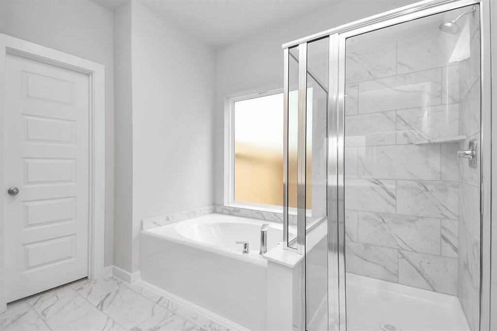 This additional view of the primary bath features a walk-in shower with the tile surround and separate garden tub perfect for soaking after a long day. Sample photo of completed home with similar floor plan. Actual colors and selections may vary.