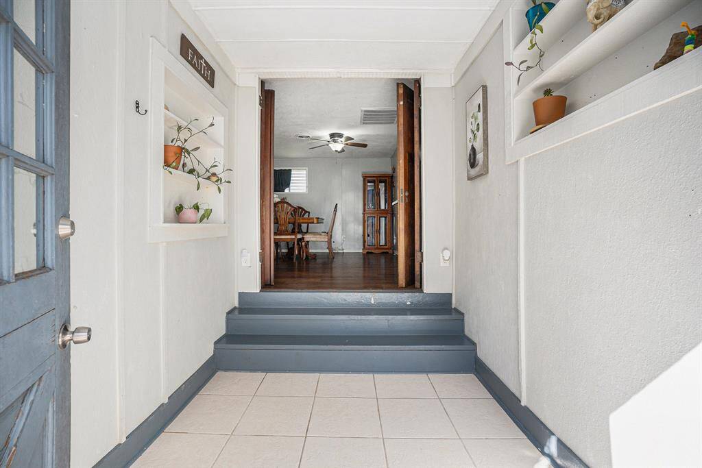 This photo shows a welcoming entryway with a few steps to a wooden-floored dining area. Built-in shelves add charm, and the space is well-lit and inviting.
