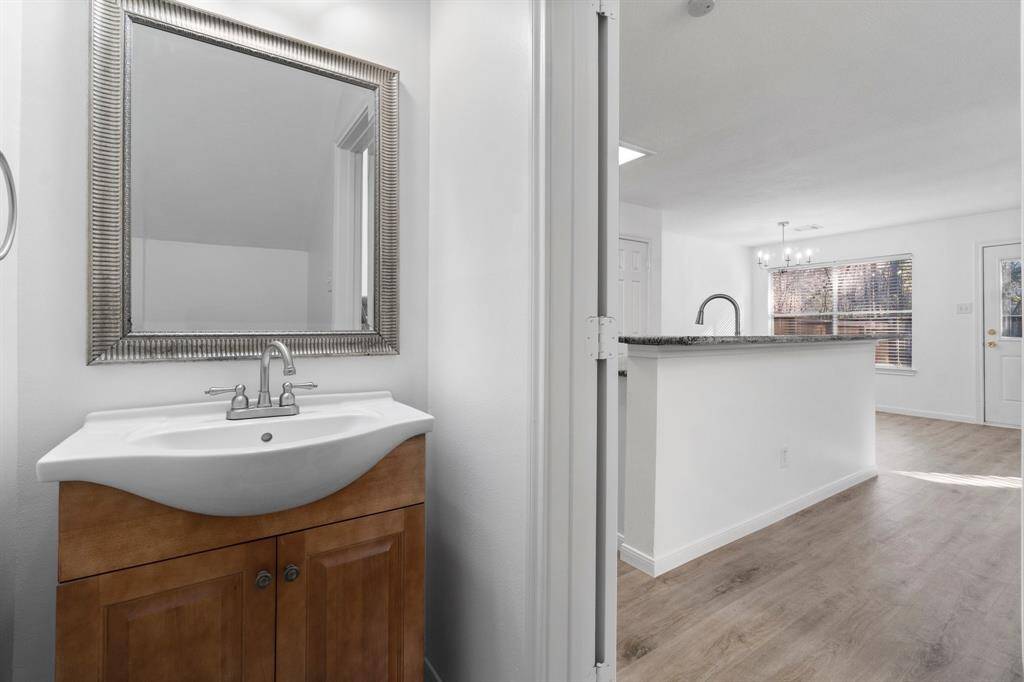 The powder room has a sleek vanity and spacious mirror, leading into the downstairs living space.