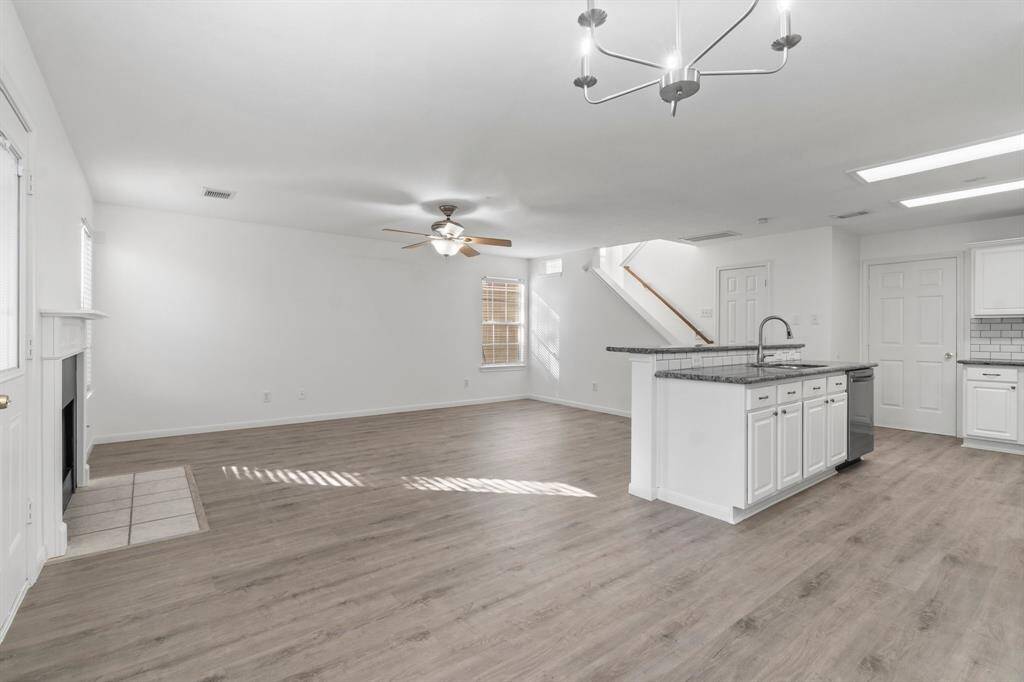 This spacious open-concept living area features a ceiling fan, recessed lighting, and a cozy fireplace, perfect for comfortable living and entertaining.