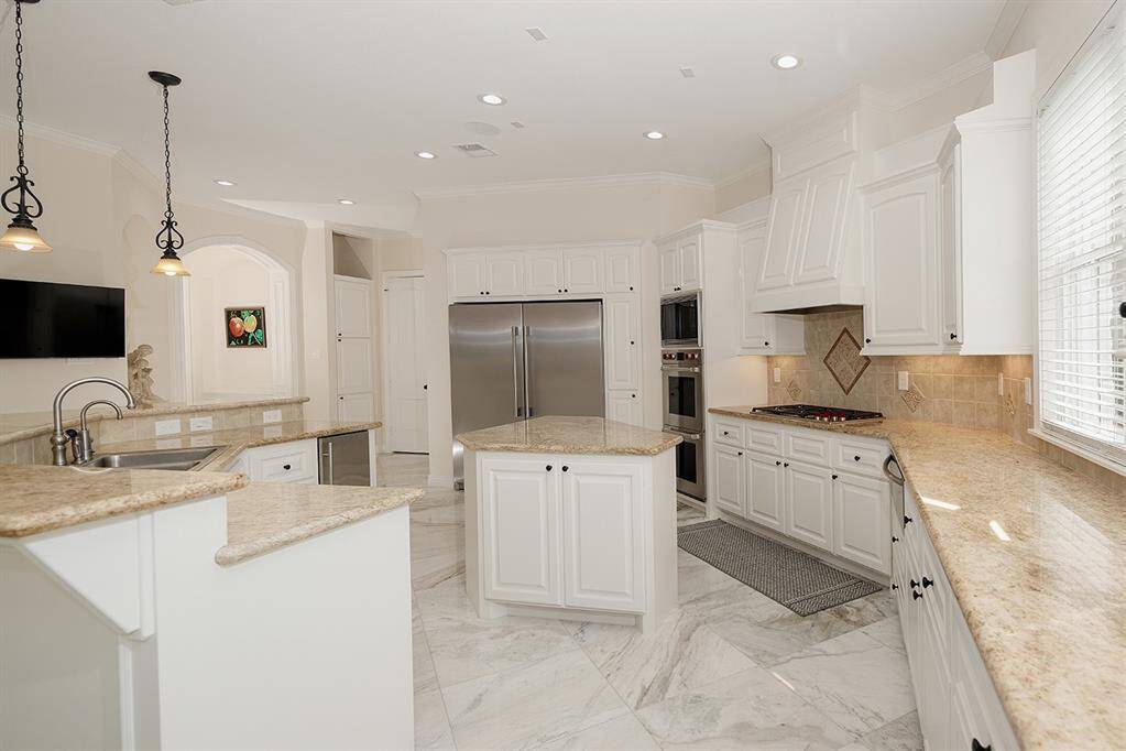 The functional island kitchen with granite counters has a gas cooktop, dual ovens with vent hood and huge built-in refrigerator
