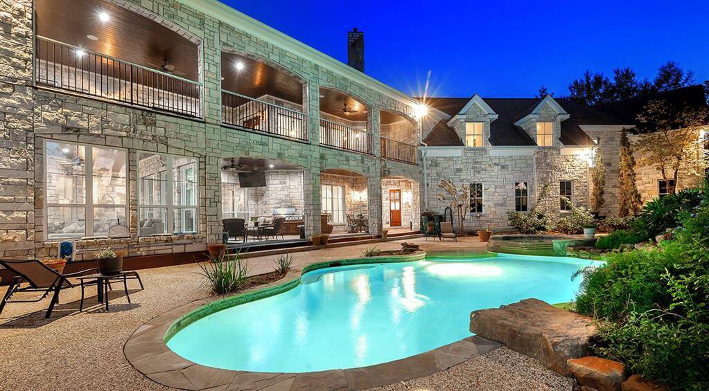 The heated pool and spa are surrounded by lush landscaping. Notice the diving rock!