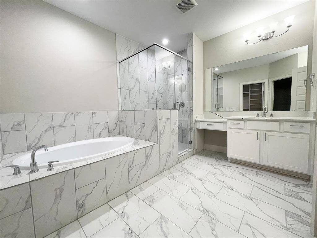 The ROClake's primary bathroom features a large shower and bathtub and dual vanities. The bright lighting fixtures and clean lines contribute to a serene, spa-like atmosphere. *Image depicts home as-is.
