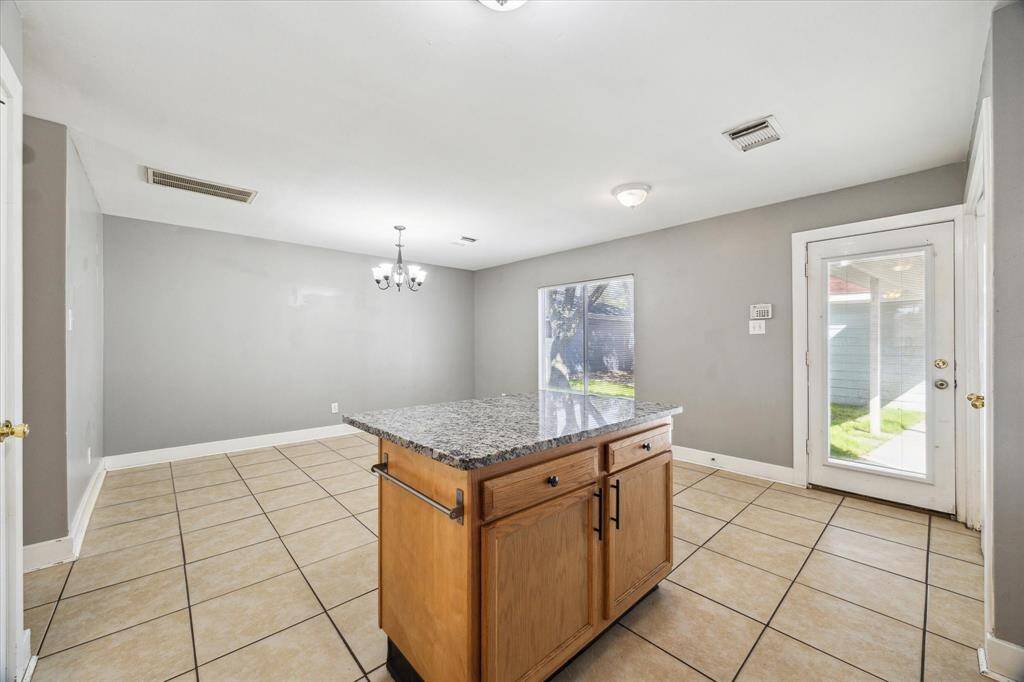 A large center island offers ample storage below, a convenient workspace for meal prep, and a bar for casual seating.